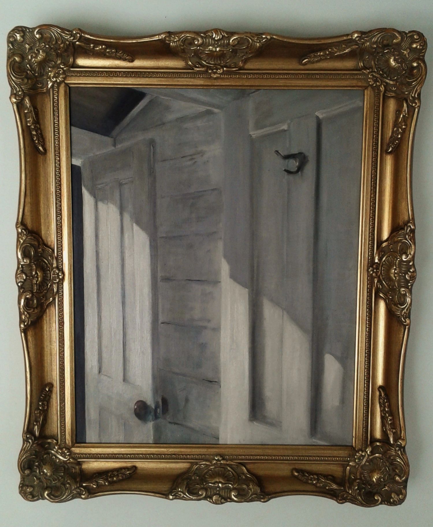 Antique gold-framed painting of a partially open door with light and shadow.