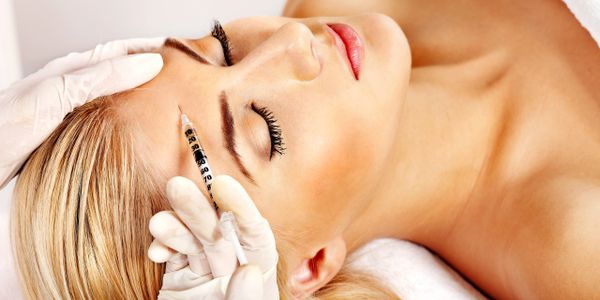Woman receiving a cosmetic injection in her forehead.