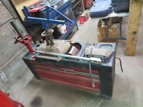 Vintage Sears SB-40A tire changer in a workshop with tools and equipment.