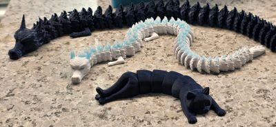 Three segmented dragon figures in black, white, and blue colors on a stone surface.