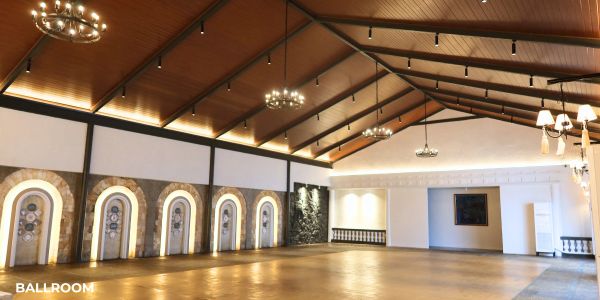 Spacious ballroom with wooden ceiling and elegant chandeliers.