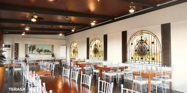 Empty restaurant dining area with wooden tables and white chairs.
