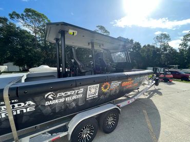 Black speedboat on a trailer under sunlight.