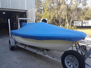 Boat on a trailer with a blue cover.