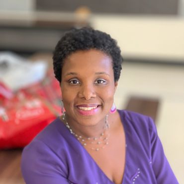 Smiling woman in a purple top with short hair.