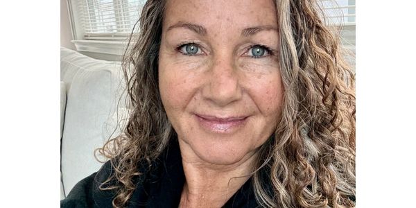 Woman with curly hair smiling gently.