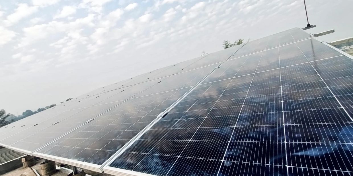 Solar panels under a partly cloudy sky reflecting light.