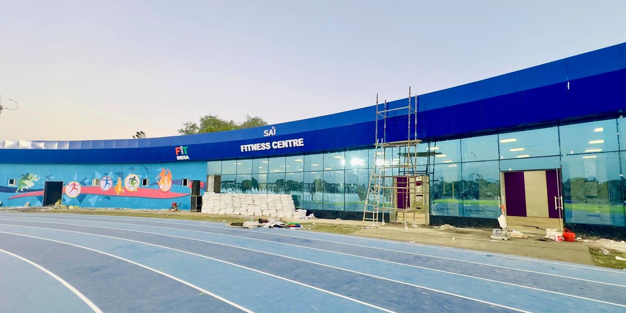 Modern fitness centre with a blue running track and colorful sports murals.
