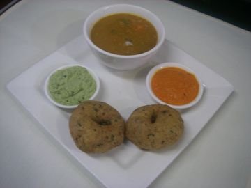 two fried lentil donuts served with samber and chutneys