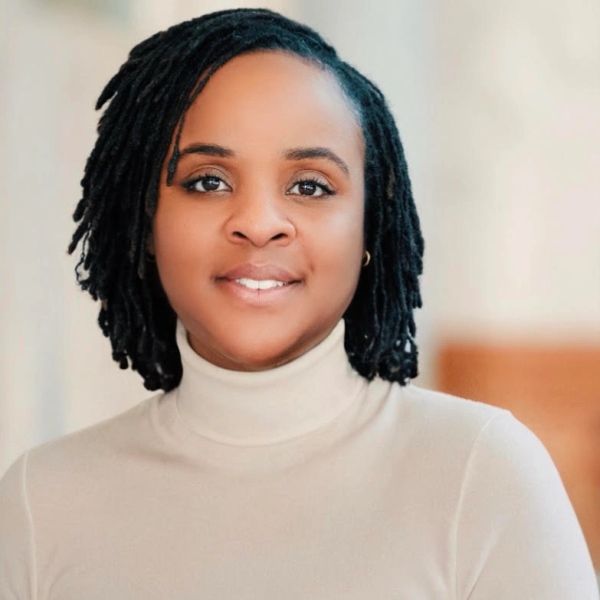 Portrait of a woman with natural hair and a beige turtleneck.