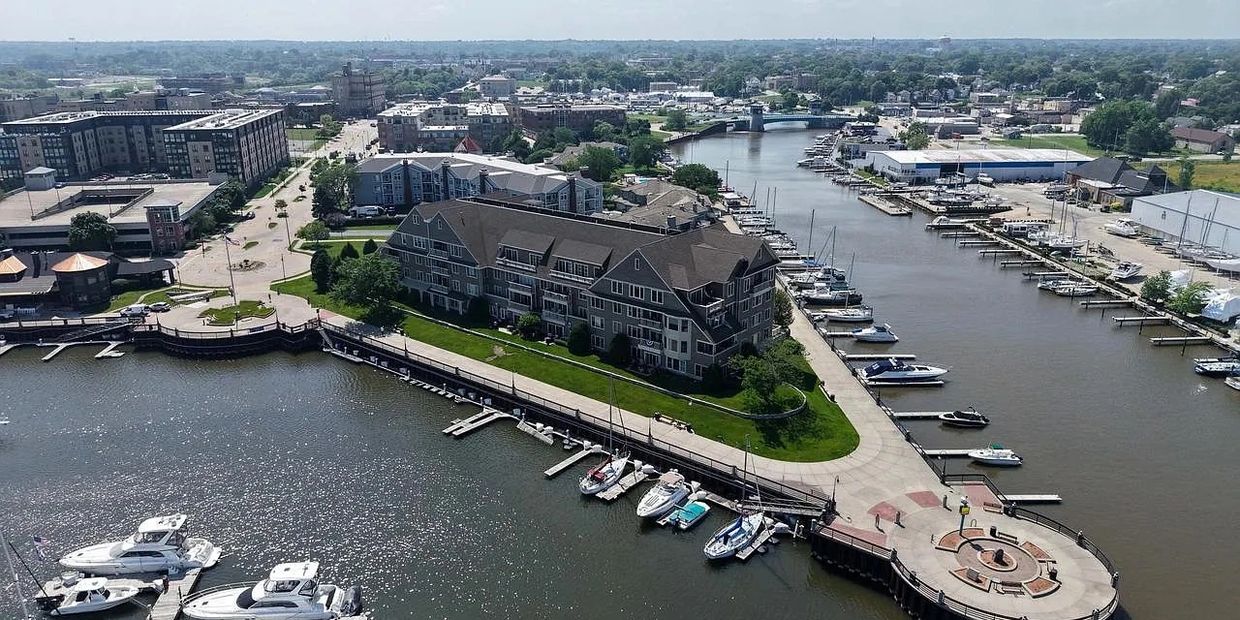 Aerial view of a marina with boats and a large building on the waterfront.
