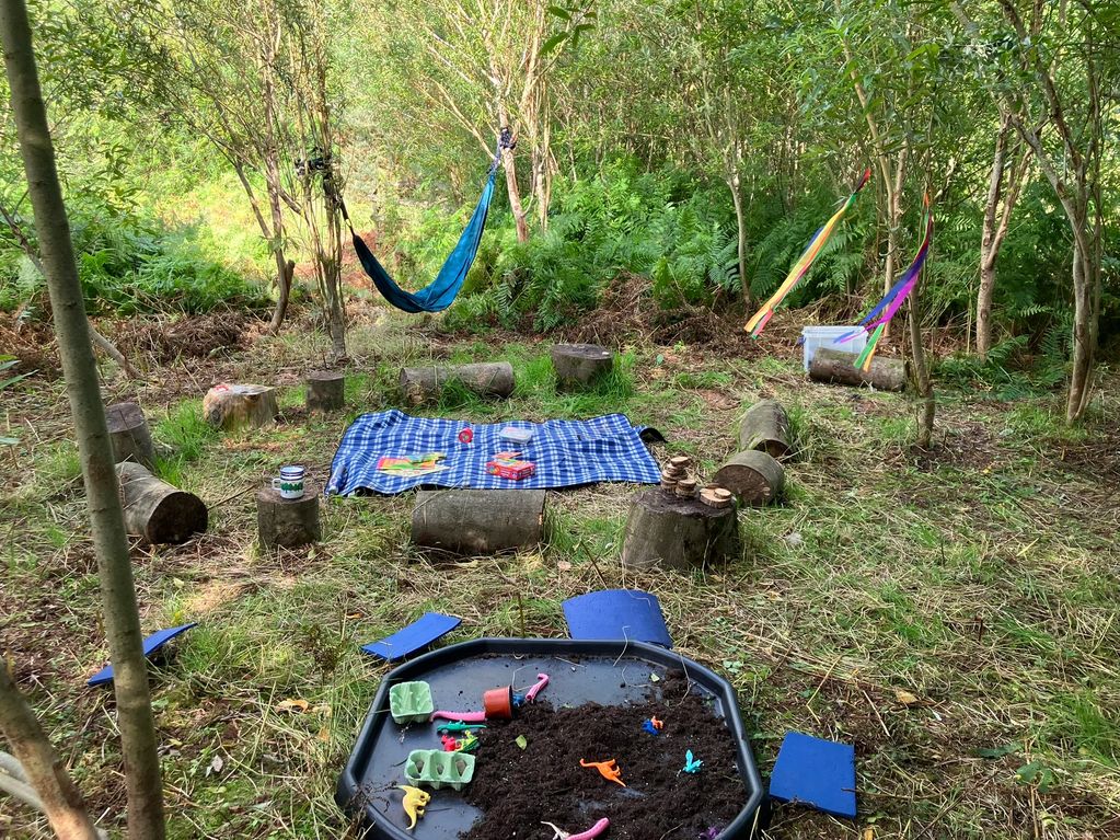 Forest school site, log circle with sensory play, sensory toys and hammock 