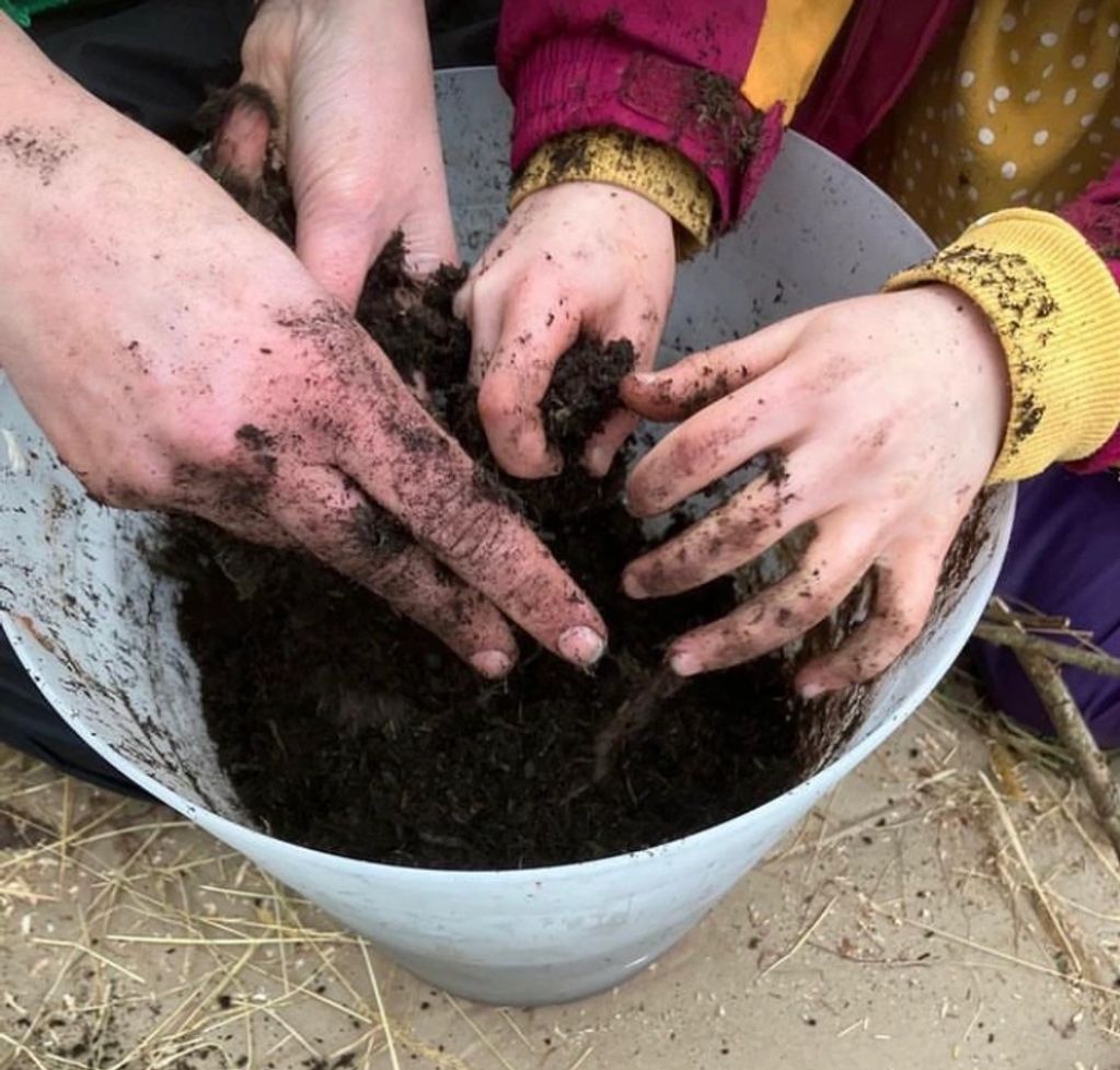 Adult and child hands in bucket of soil for Sensory play, messy play