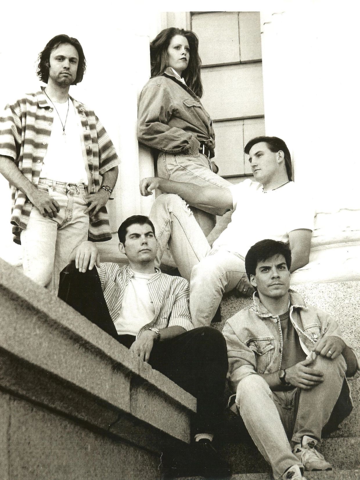 Group of five people posing outdoors in casual 90s fashion.