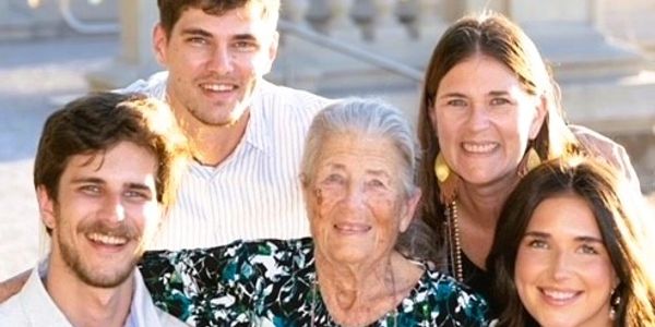 Smiling family with an elderly woman outdoors.