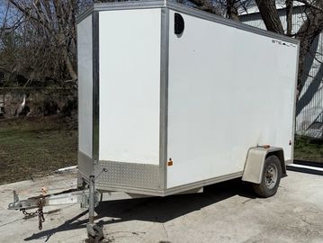 White enclosed trailer parked on a concrete surface outdoors.