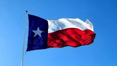 Texas state flag waving against a clear blue sky.