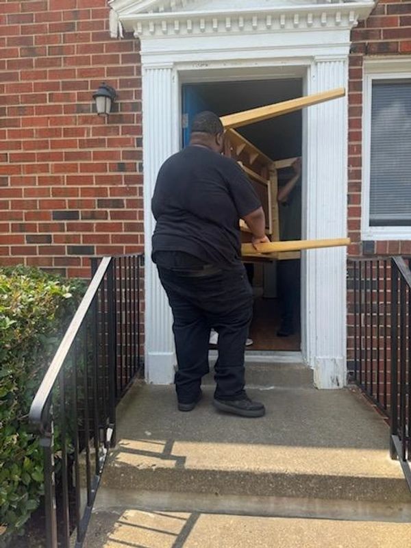 Volunteers carrying table inside a house.