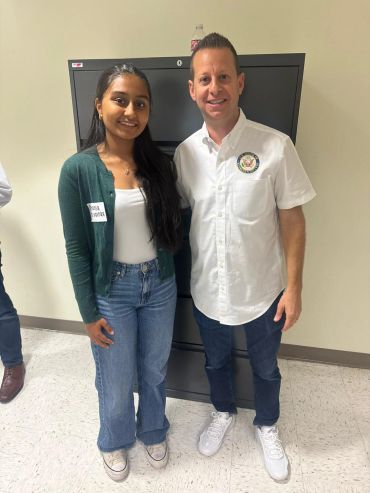 A young woman and a man standing indoors, posing for a photo.