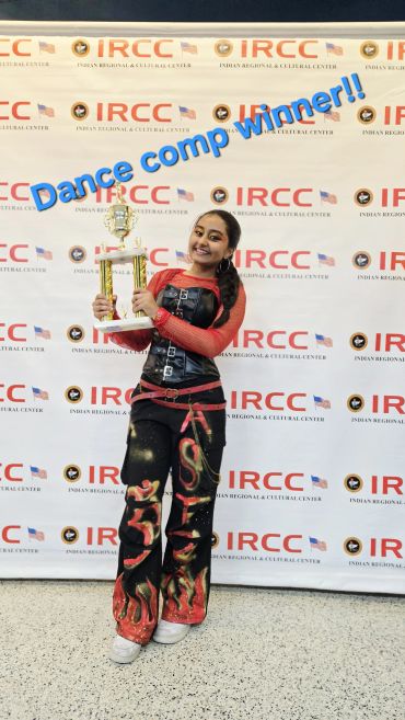 Girl holding a dance competition trophy, smiling.