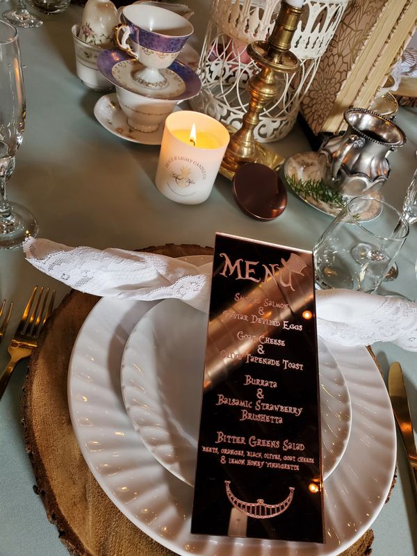 Peace & Light Candle sitting on table next to a rose gold mirror with a menu etched on it.