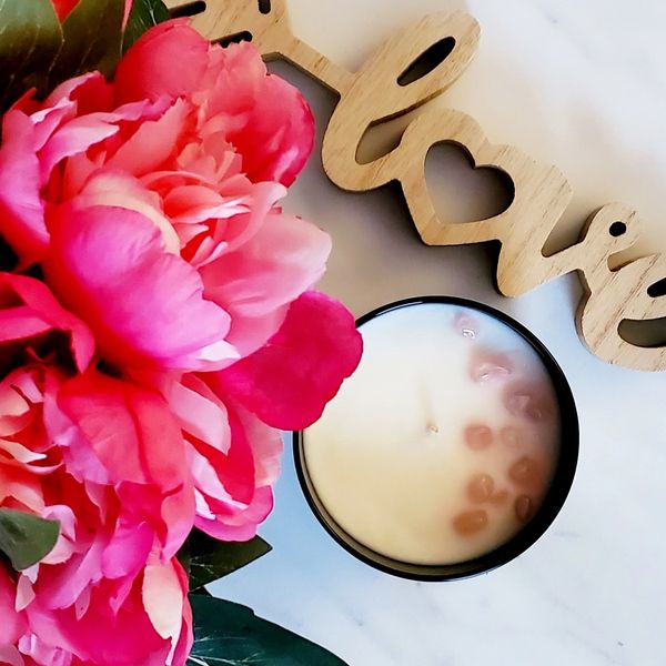 Candle with Rose Quartz Crystals, peony flowers, and the word love. 