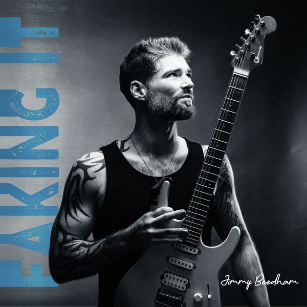Bearded man with tattoos holding electric guitar, looking away thoughtfully.