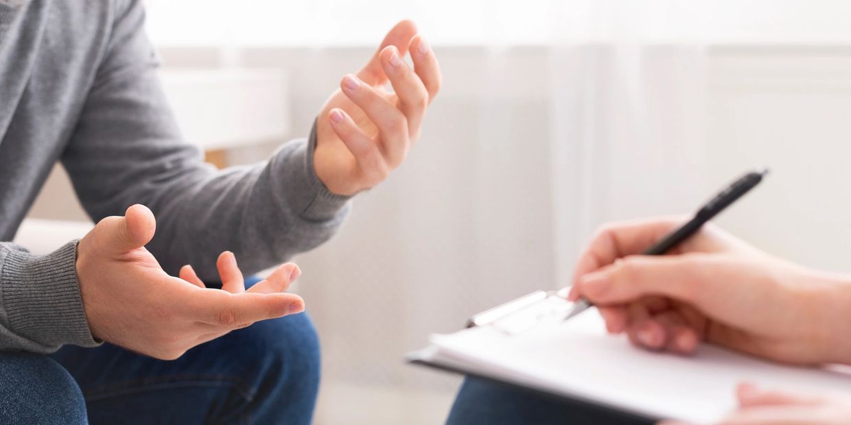 Person discussing while another writes on a clipboard.