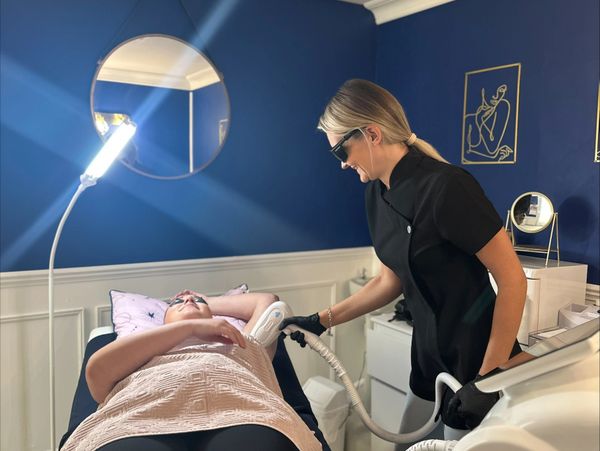 A technician performs a laser treatment on a patient's underarm in a modern clinic.
