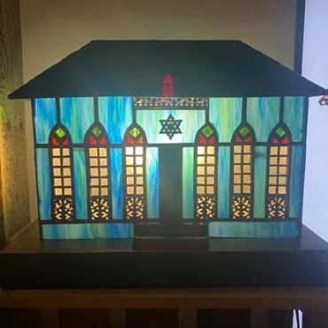 A decorative stained glass model house with blue-tinted windows.