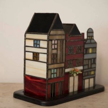 Stained glass model of three houses on a black base.