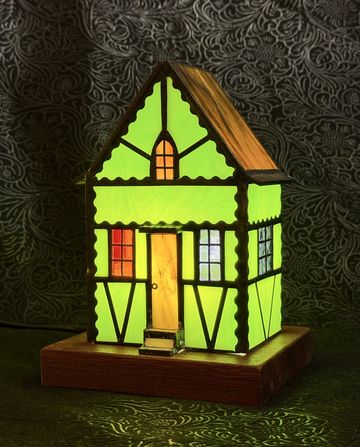 Glowing green miniature house lamp on wooden base.