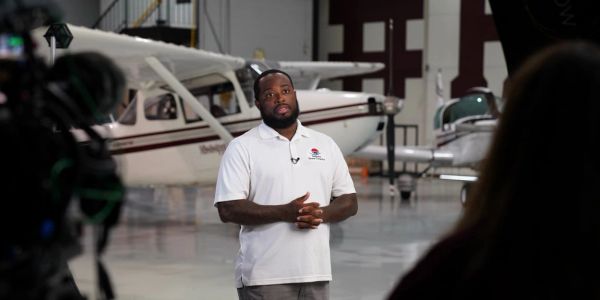 Man being interviewed in an airplane hangar.