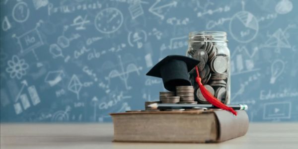 Graduation cap on coins with book and jar of coins.