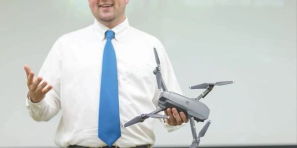 Man holding a drone and explaining.