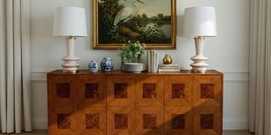 Elegant wooden sideboard with decorative lamps, vases, and painting.