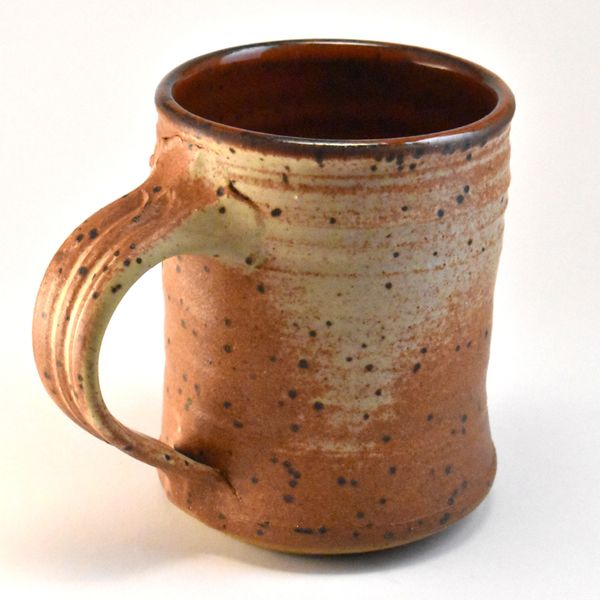 Handmade ceramic mug with speckled glaze and earthy tones.