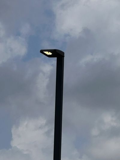 A street lamp glowing against a cloudy sky.
