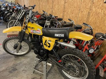A vintage yellow Suzuki RM250 motocross bike with number 45 parked indoors.