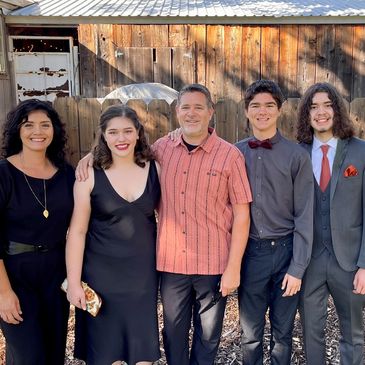 Five members of the family business smiling while standing shoulder to shoulder in front of a barn.