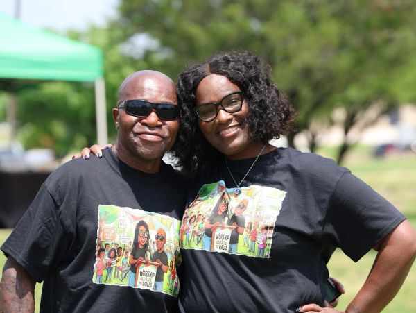 Two people smiling, wearing matching black t-shirts outdoors.