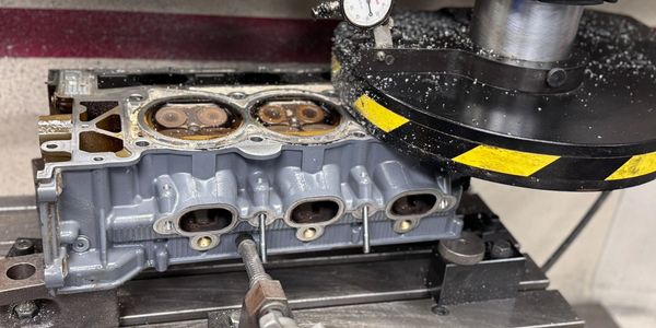 Machining a metal engine cylinder head on a precision milling machine.