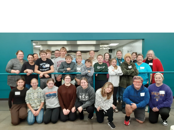 Group photo of diverse students and adults smiling indoors.