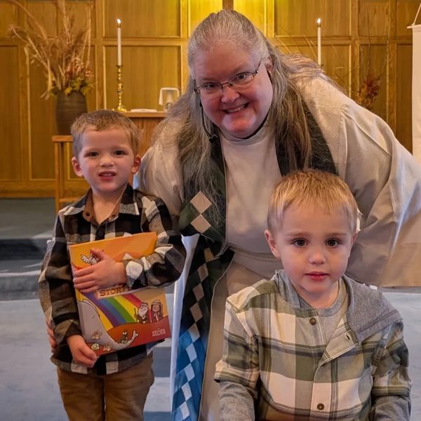 A woman in religious attire with two young boys inside a church.