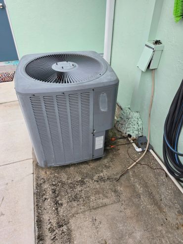 Outdoor air conditioning unit installed beside a house wall.