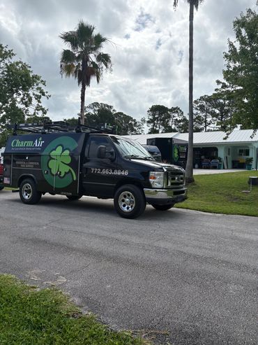 CharmAir service van parked on a residential street with palm trees.
