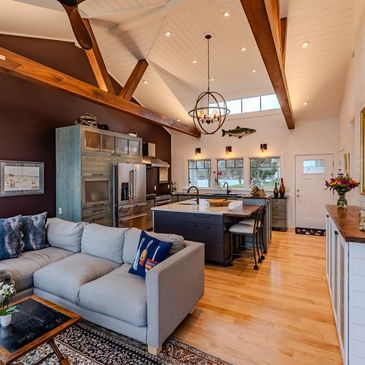 Cozy modern kitchen and living room with wooden beams and high ceilings.