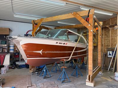 Classic wooden boat suspended on stands inside a workshop.