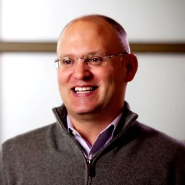 Smiling bald man wearing glasses and a gray sweater.