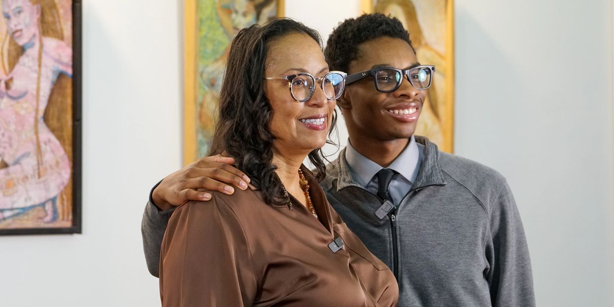 A smiling woman and young man posing together in an art gallery.